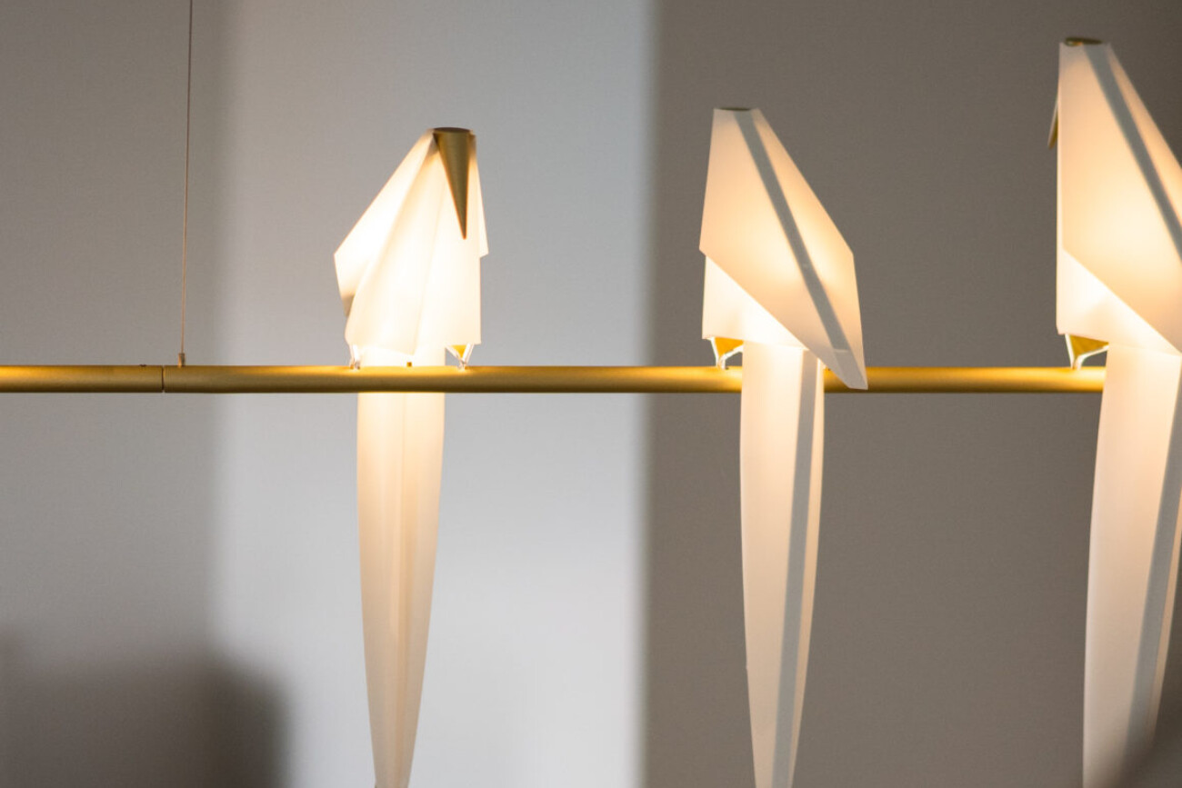 bird lighting feature perched on a hanging branch inside a home